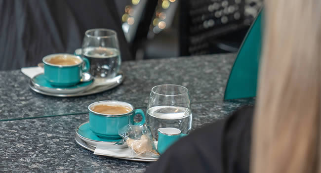 Kunde während der Beratung mit einer Tasse Kaffee und einem Glas Wasser.