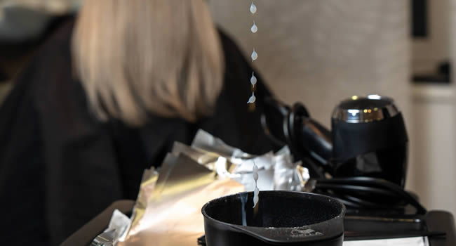 Friseur bereitet eine Haarfärbung vor, indem er die Farbe mischt.